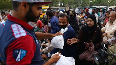 People receive free food as time to break the fast approach on the road during Ramadan amid lockdown of the Sindh province due to the ongoing pandemic, in Karachi, Pakistan. EPA