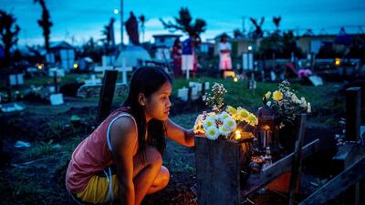 A woman tends to the gravesite of a loved one at the makeshift mass grave site at San Joaquin Parish on April 16, 2014 in Tacloban, Leyte, Philippines. Chris McGrath / Getty Images