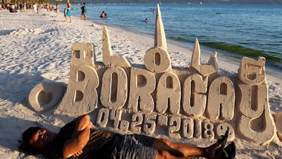 A tourist poses in front of a sand sculpture, a day before the temporary closure of the holiday island Boracay. Erik De Castro / Reuters
