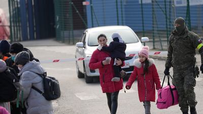 A woman fleeing Ukraine carries a child as she crosses the border in Vysne Nemecke, Slovakia. AP