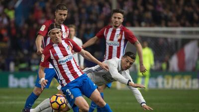 Real Madrid’s Portuguese forward Cristiano Ronaldo, right, falls past Atletico Madrid’s Brazilian defender Filipe Luis. Curto de la Torre / AFP