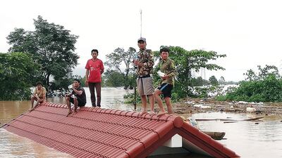 Lao villagers are stranded on the roof of a house after flash flooding. EPA