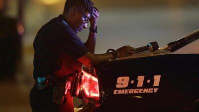 A Dallas police officer, who did not want to be identified, takes a moment as she guards an intersection in the early morning after a shooting in downtown Dallas. At least two snipers opened fire on police officers during protests in Dallas on Thursday night. LM Otero / AP