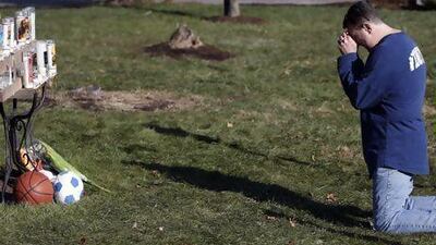 A man weeps while praying in front of a memorial for shooting victims outside Saint Rose of Lima Roman Catholic Church yesterday.