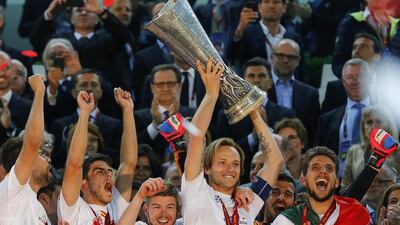 Sevilla captain Ivan Rakitic lifts the Europa League trophy as his teammates celebrate after defeating Benfica in Turin, Italy, on May 14, 2014. Sevilla won 4-2 on penalties. Armando Babani / EPA