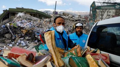 People collect copies of holy books from the rubble in Kahramanmaras. Reuters