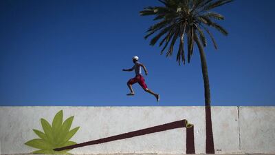 A man runs along a mural by Polish artist M-CITY decorating a wall in the village of Erriadh. Joel Saget / AFP Photo