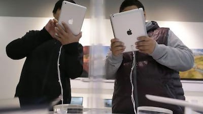A sales assistant (left) holds an iPad mini next to a customer holding an iPad during the launch of the iPad mini in China.
