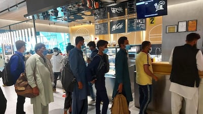 Pakistani passengers queue for free meals after being told they could not leave Dubai International Airport. Consulate General of Pakistan in Dubai
