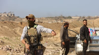 An armed man at a checkpoint overseen by US and Egyptian security at the Netzarim Corridor as displaced Palestinians make their way to northern Gaza. AFP