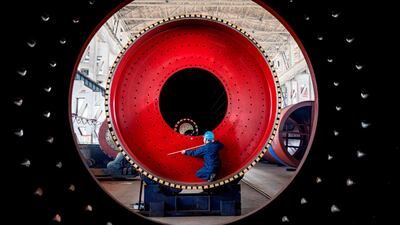 An employee measures a newly manufactured ball mill machine at a factory in Nantong, Jiangsu province, China. Reuters