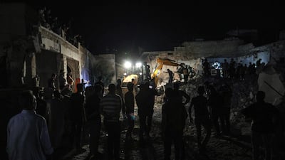People watch as members of the Syrian Civil Defence, also known as the "White Helmets", attempt to clear debris as they search for bodies or survivors in a collapsed building following a reported government air strike in the village of Saraqib in Syria's northwestern Idlib province. AFP