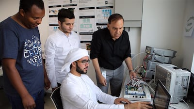 The director of the Khalifa University semiconductor research centre, Prof Mohammed Ismail (in black), and his team members, from left, Jonatan Kifle, Mohammad Al Hawari, and Saif Al Junaibi, look at results for their new device. Ravindranath K / The National