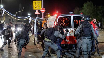 An Israeli border guard officer hits a Palestinian with a baton near an ambulance. AFP