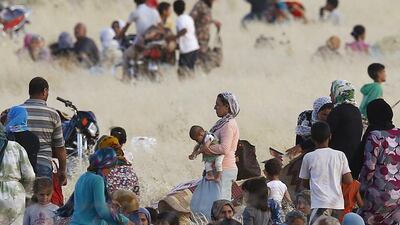 Syrian Kurds fleeing Kobani wait near the border with Turkey on June 26, 2015, a day after the town was attacked by ISIL. Murad Sezer / Reuters