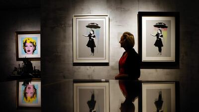 A woman stands next to a piece by British artist Banksy at a retrospective exhibition in Munich, Germany. Matthias Schrader / AP Photo