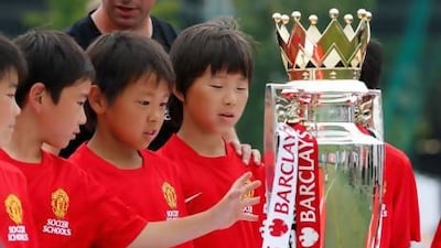 A boy tries to touch the Premier League's champion trophy during Manchester United soccer schools in Yokohama, near Tokyo.