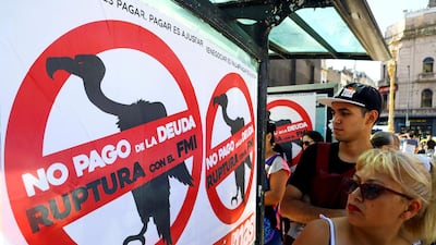 Pedestrians walk past posters on a Buenos Aires street urging Argentina to default on its debt and break with the IMF. Reuters