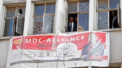 People peer through the windows of the headquarters of the opposition Movement for Democratic Change (MDC) party. Reuters