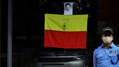 A private security guard stands beside a Kannada flag and a photograph of the late actor Dr Rajkumar, put up on the glass pane of a car showroom, after the news spread of his son and actor Puneeth Rajkumar's critical health state, in Bengaluru. AFP