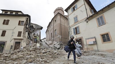 A resident carrying his belongings passes in front of the collapsed bell tower of the Santa Maria in Via church in the town of Camerino, in central Italy, on October 27, 2016, a day after a 5.9 earthquake destroyed part of the town. Alessandra Tarantino/ AP Photo