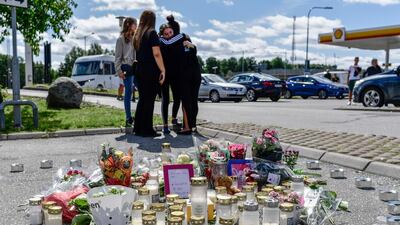 People gather near to where a twelve-year-old girl was shot and killed near a petrol station in Botkyrka, south of Stockholm, Sweden, Monday Auust 3, 2020. TT via AP