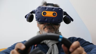 An attendee wears a McLaren branded HTC Vive Pro headset and sits inside a driving module to play a virtual reality (VR) F1 racing game on day two of the MWC. Bloomberg