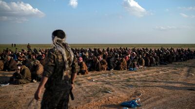 US-backed Syrian Democratic Forces (SDF) fighters stand guard next to men waiting to be screened after leaving the last territory held by ISIS in Syria. AP