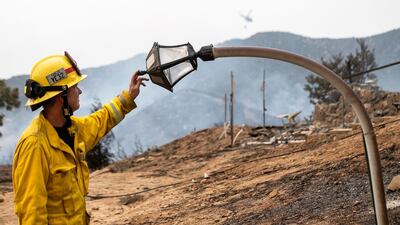 Fire engineer, Paul Kahler, of Fountain Valley, Cailfornia, examines a melted light post where a structure was destroyed by the El Dorado wildfire near Yucaipa. AP