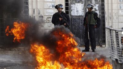 Israeli police stand over burning tyres during clashes with stone-throwing Palestinians following Friday prayers in the West Bank city of Hebron on November 21, 2014. Abed Al Hashlamoun / EPA