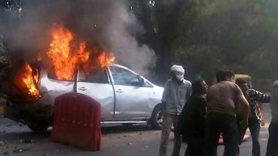 Indian bystanders tend to an Israeli diplomat (partially obscured, on the ground) following a car bomb explosion near the Israeli embassy in New Delhi on February 13.