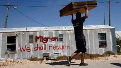 An Israeli moving company employee carries cardboard boxes as he walks past a caravan of evacuated settlers in the Migron outpost in the occupied West Bank.