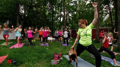 Casey Chaffin pets a goat while performing a yoga pose. Carrie Antlfinger / AP Photo
