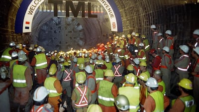 French and British workers look at the tunnel-boring machine Europa during the link-up in the north gallery of the Channel Tunnel on May 22, 1991. / AFP