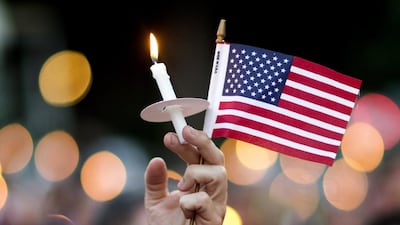 A mourner holds up an American flag and a candle during a vigil for the victims of the fatal shooting at an Orlando nightclub, in Atlanta. David Goldman / AP
