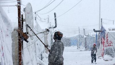 A Syrian man removes the snow from his TV satellite aerial at the refugee camp. Hussein Malla / AP Photo