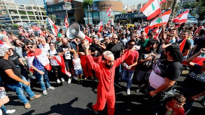 A Lebanese protester, wearing a mask of the Spanish TV show "La Casa de Papel", chants slogans on the highway linking Beirut to north Lebanon, in Zouk Mikael on October 19, 2019.