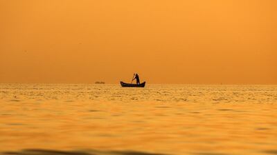 As the sun sets a fishermen paddles his boat along the Arabian Sea coast of Mumbai. Divyakant Solanki / EPA