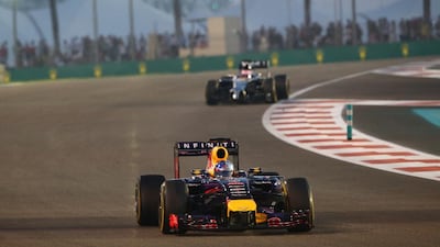 Vettel drives ahead of McLaren's Jenson Button as the flood lights come on at Yas Marina Circuit. Marwan Namaani / AFP Photo