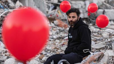 Turkish man Ogun Sever Okur sits among balloons hanging from the debris of a collapsed building in Antakya, southern Turkey. AFP
