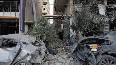 A Palestinian woman stands by a damaged building and destroyed cars on Tuesday following Israeli airstrikes on Gaza City. AFP