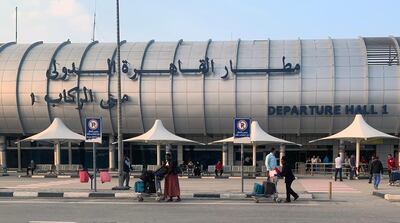 People stand outside the airport in Cairo, Egypt. All international flights will be suspended from March 19 over coronavirus concerns. EPA