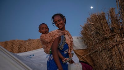 A Tigray woman who fled the conflict in Ethiopia's Tigray region, carries her baby near her shelter, at Umm Rakouba refugee camp in Qadarif, eastern Sudan. AP Photo