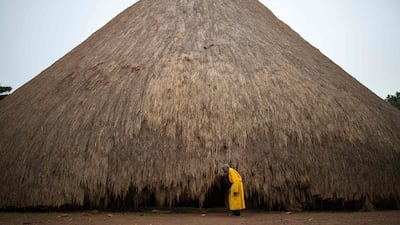 (FILES) A traditional guard stands in front of one of the buildings belonging to the Kasubi Royal Tombs in Kampala, Uganda on June 13, 2023. The World Heritage Committee, meeting in Riyadh until September 25, 2023 decided on September 12, 2023 to remove the Kasubi Royal Tombs from the List of World Heritage in Danger following the restoration work carried out successfully by Uganda in coordination with UNESCO. (Photo by Stuart Tibaweswa / AFP)