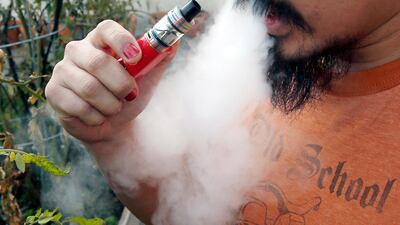 A man blows a puff of smoke as he vapes with an electronic cigarette. AP Photo / Jim Mone