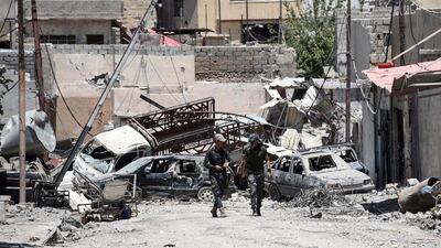 Iraqi soldiers walk down a street barricaded with vehicles in Mosul’s western Al Shifaa district on June 15, 2017. Mohamed El Shahed / AFP