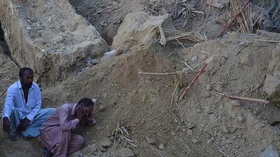 A Pakistani mourner talks on a mobile phone at the site of a landslide in Karachi. Asif Hassan / AFP