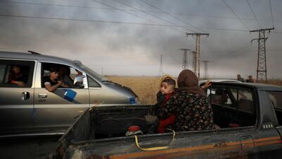 A woman with a baby sits at a back of a truck as they flee Ras Al Ain town, Syria. Reuters