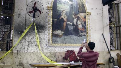 A man takes pictures of the destruction, debris and bloodstains on the walls inside the Mar Girgis Coptic Orthodox Church in the Nile Delta City of Tanta, north of Cairo. AFP