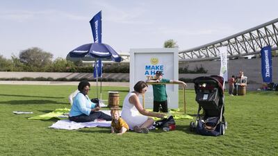 April Robinson, Lisa Pearson and Kevin Jeffers help out at a newspaper hat making station at the picnic in Umm Al Emarat Park.